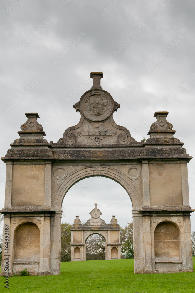 Stone monument with two arches in a formal English garden