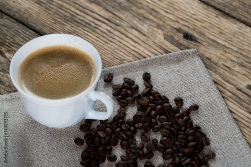 Coffee cup and beans on a wooden table.