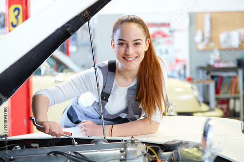 Young female mechanic working on car engine photo