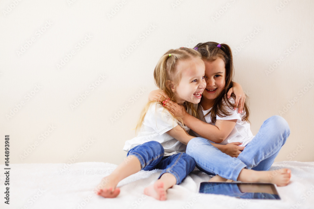 Two little girls using a touch pad family, children, technology and home concept happy little girls with tablet pc computers Two little girls using a touch pad family, children, technology and home concept happy little girls with tablet pc computers