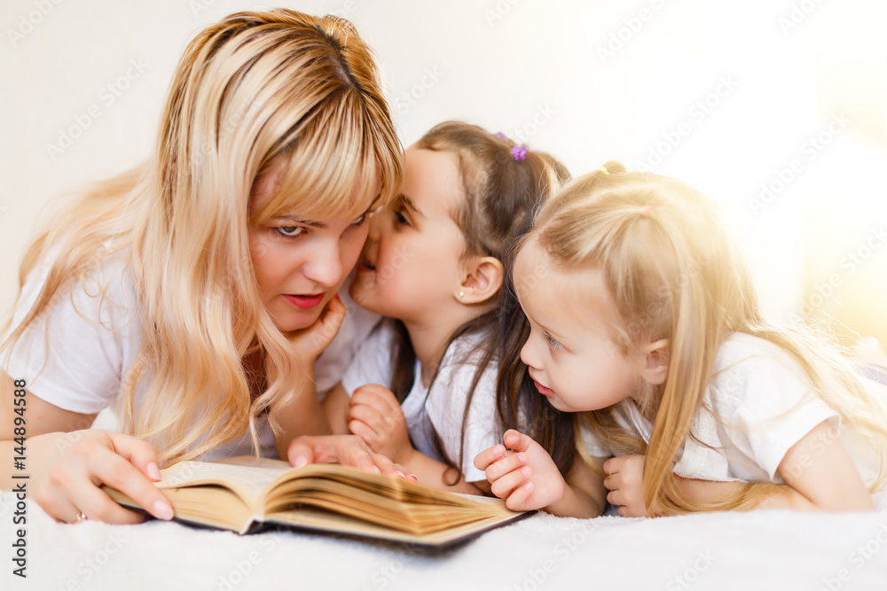 happy loving family. pretty young mother reading a book to her daughters happy loving family. pretty young mother reading a book to her daughters