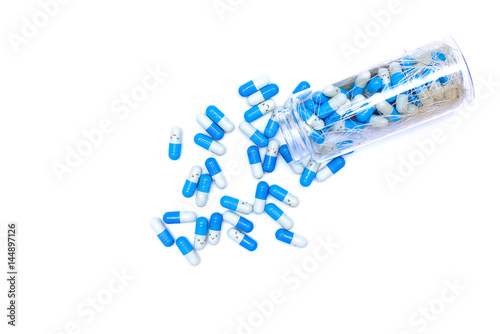 blue medical capsules pills spilling out of pill bottle isolated on white background