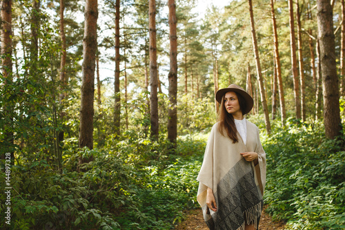 A girl in a poncho and a hat in forest