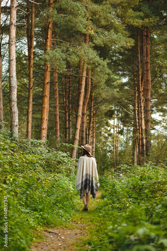 A girl in a poncho and a hat in forest