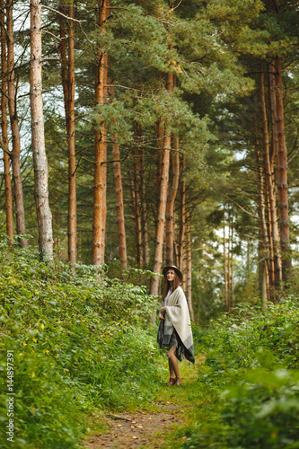 A girl in a poncho and a hat in forest
