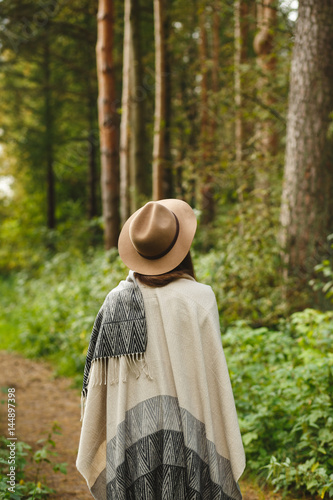 A girl in a poncho and a hat in forest