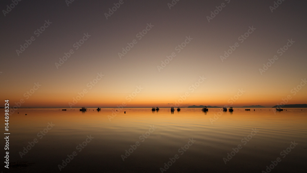 A warm sunset on a calm water, with Islands in the background