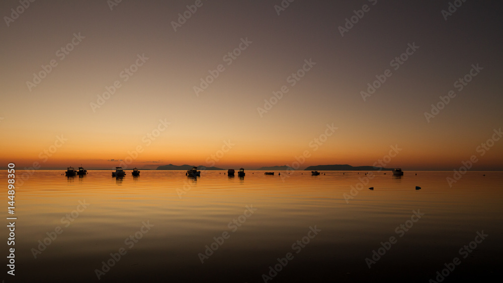 A warm sunset on a calm water, with Islands in the background A warm sunset on a calm water, with Islands in the background