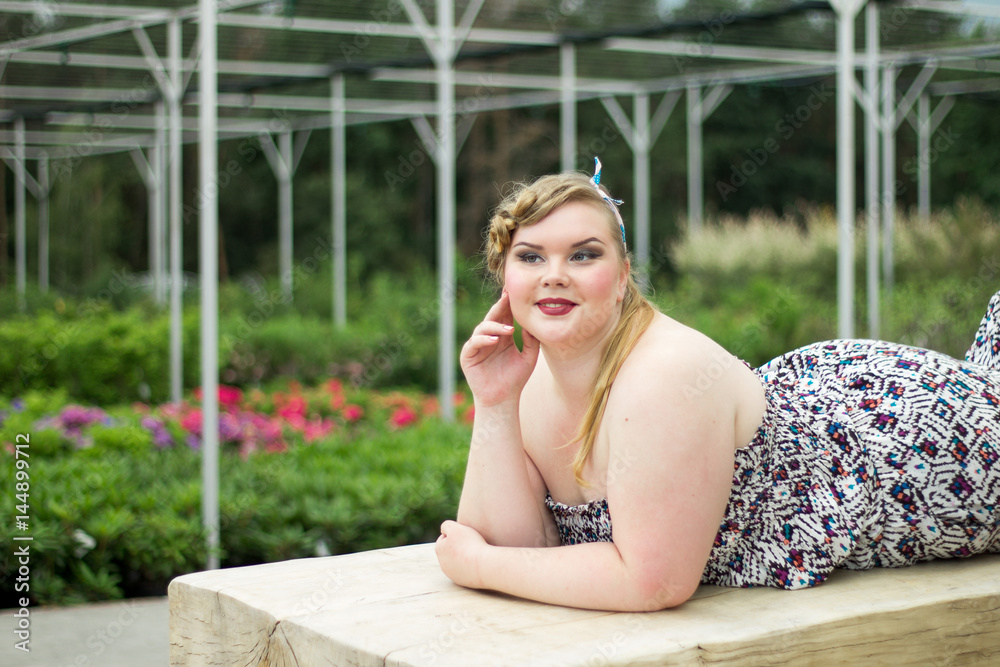 Young beautiful plus size girl is lying on wooden bench. Young beautiful plus size girl is lying on wooden bench.