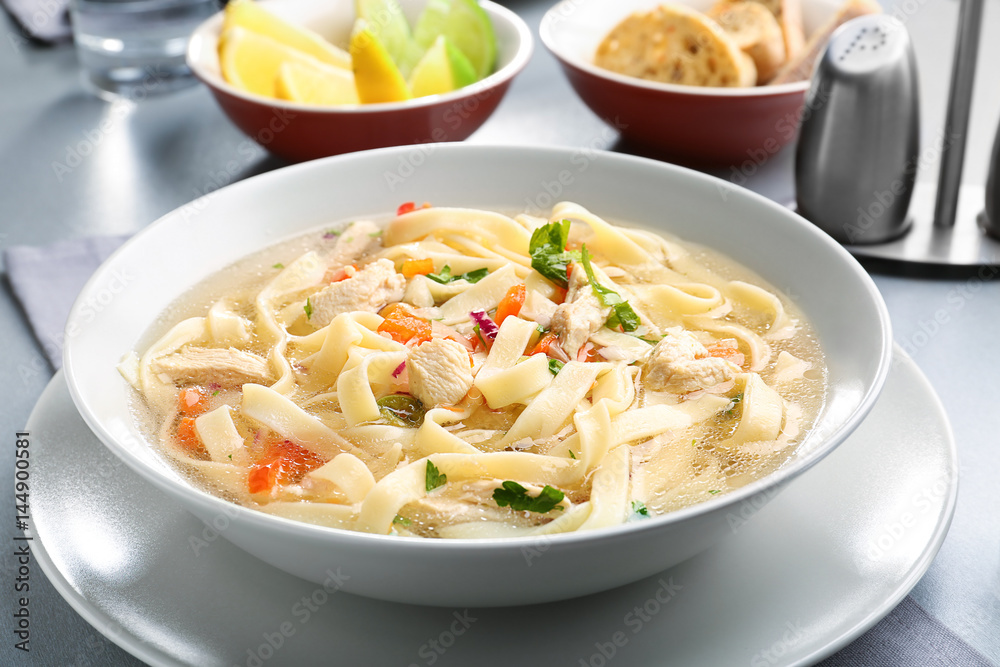 Chicken noodle soup in plate on kitchen table