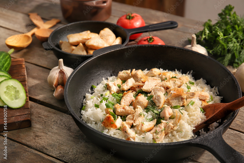 Frying pan with chicken and rice on kitchen table Frying pan with chicken and rice on kitchen table
