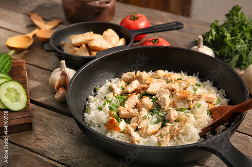 Frying pan with chicken and rice on kitchen table