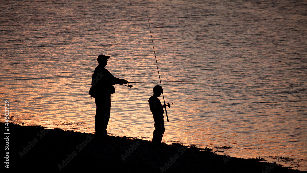 Silhouettes of father and son fishing on the lake in sunset Stock Photo ...
