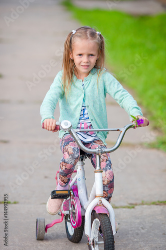 Adorable girl riding a bike at beautiful summer day outdoors