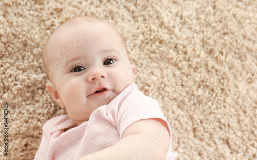 Portrait of adorable baby on light carpet background