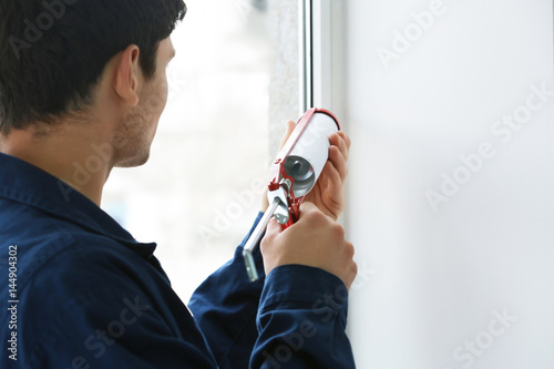 Slika na platnu Young worker sealing joints of office window