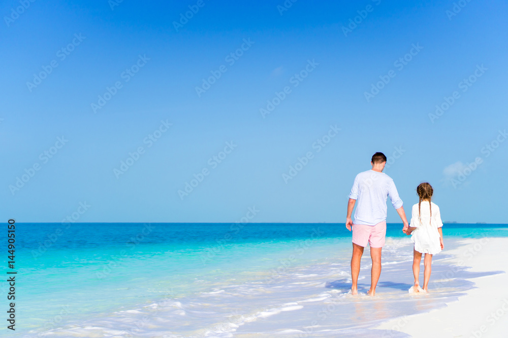 Happy dad and little girl enjoying beach walking on the seashore