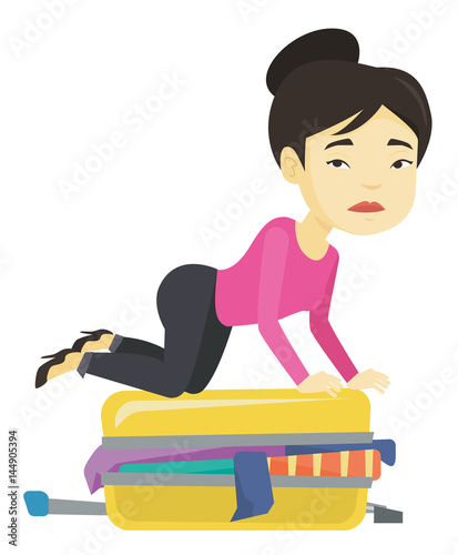 Young woman trying to close suitcase.