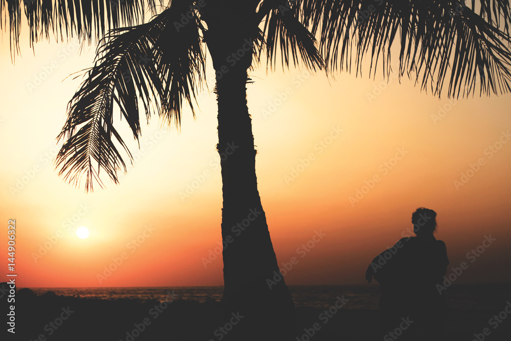 hübsche Frau sitzt bei Sonnenuntergang am Strand