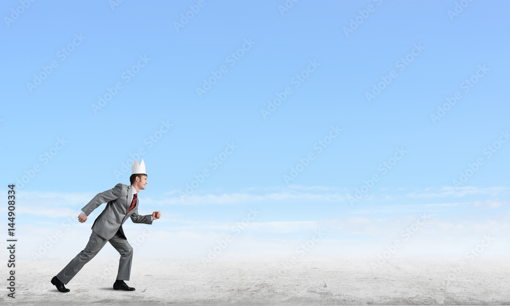 King businessman in elegant suit running and blue sky at background King businessman in elegant suit running and blue sky at background