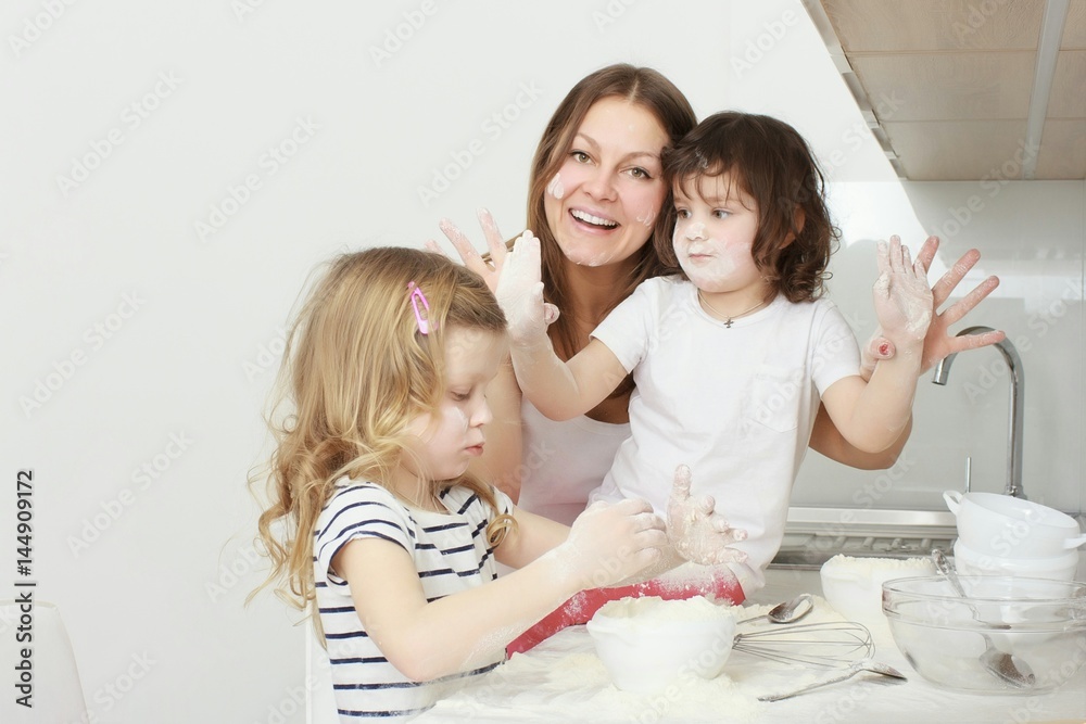 Mother with her 5 years old kids cooking holiday pie in the kitchen Mother with her 5 years old kids cooking holiday pie in the kitchen