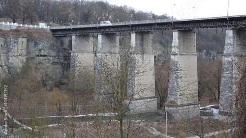 Novoplanovskiy bridge in Kamianets-Podilskyi city, located in historic region of Podolia in western Ukraine. Cars and people on stone bridge above Smotrych river in Kamianets-Podilskyi, length 136 m photo