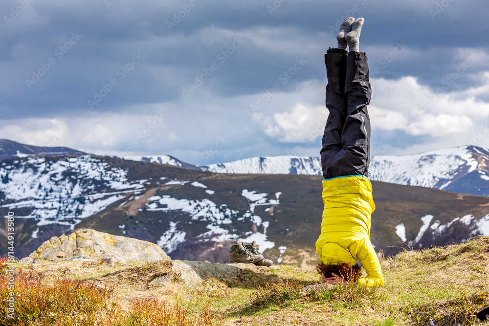 a woman in yoga asana is standing on the top of the hill, yellow jacket, sunny day. a woman in yoga asana is standing on the top of the hill, yellow jacket, sunny day.