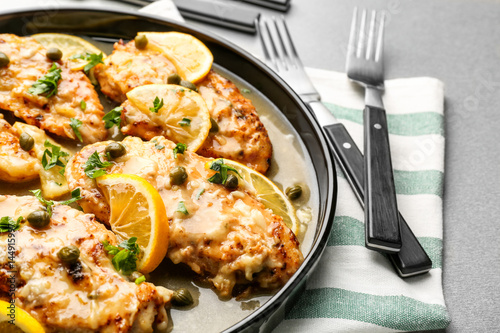 Delicious chicken piccata with sauce and lemon on plate photo