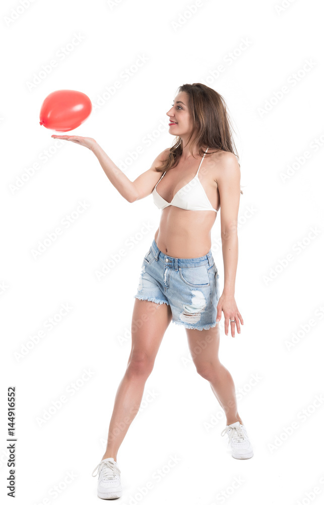 Beautiful young brunette woman in white bikini playing with red heart shape balloon isolated on white background Beautiful young brunette woman in white bikini playing with red heart shape balloon isolated on white background