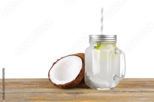 Mason jar with coconut water and fresh nut on white background