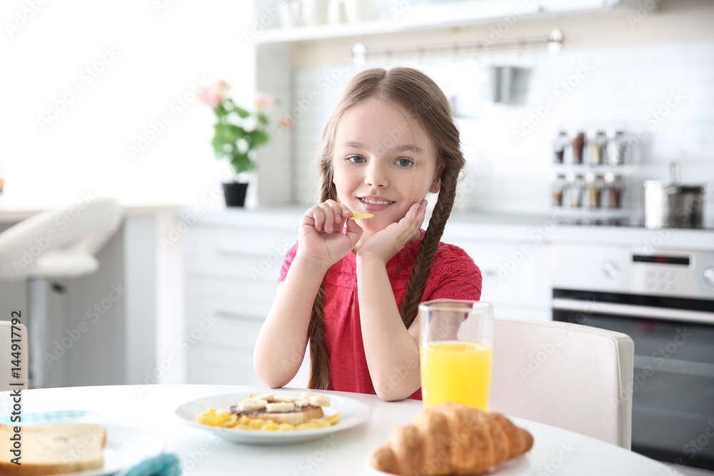 Cute little girl having breakfast at home