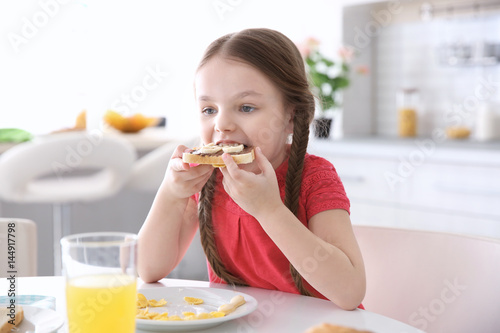 Cute little girl having breakfast at home