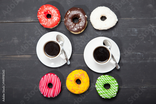 Two cups with coffee and donuts on a black wooden table