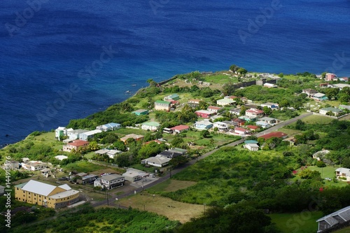A top view over seashore of Saint Kitts Island, St. Kitts and Nevis with residential buildings, roads and sea water in a bright sunny day © notsunami
