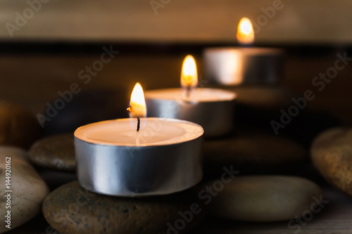 Row of candles light on pebble romantic spa background with copy space