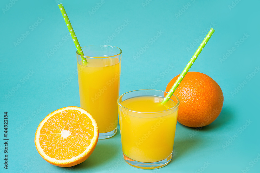 Glasses of orange juice with straw and slices on bright background Glasses of orange juice with straw and slices on bright background