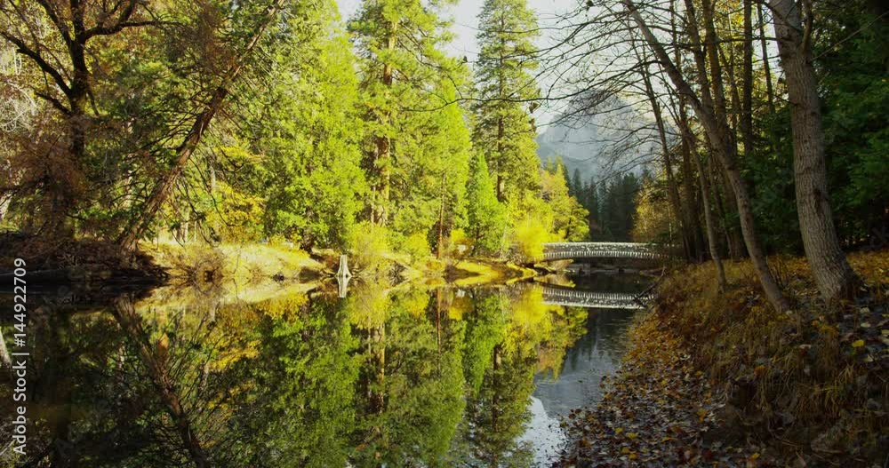 Mountains are reflected in Merced River at Yosemite National Park, California. Half Dome and Sentinel Bridge can be seen in the distance. Mountains are reflected in Merced River at Yosemite National Park, California. Half Dome and Sentinel Bridge can be seen in the distance.