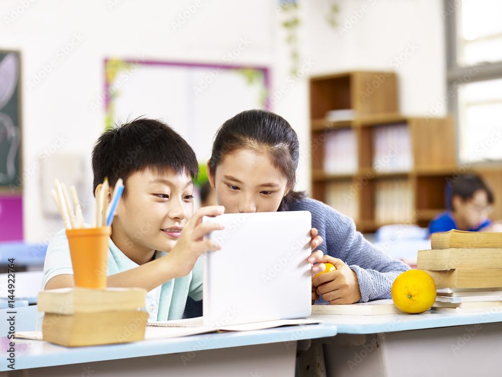 asian elementary school girl and schoolboy using tablet together asian elementary school girl and schoolboy using tablet together