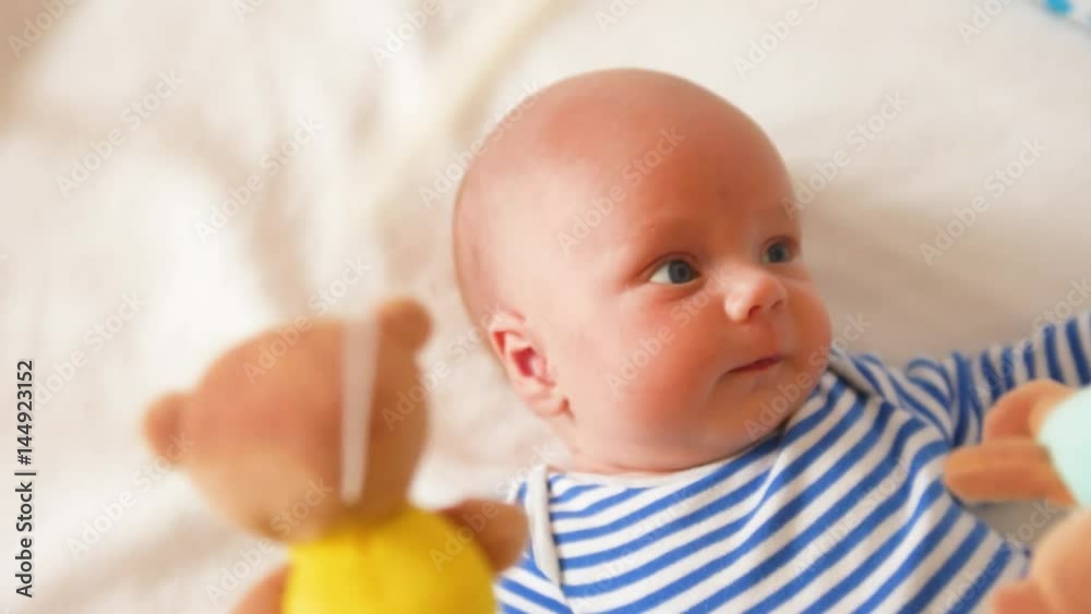 Top view shot of cute baby with soother lying in crib and looking at spinning mobile Top view shot of cute baby with soother lying in crib and looking at spinning mobile
