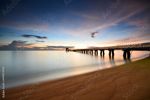 Long exposure shot of seascape with long jetty background at dusk.