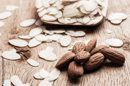 sliced and whole raw almonds on wooden surface