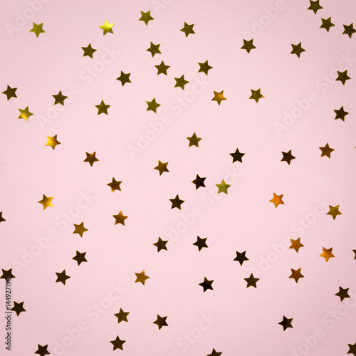 Golden star sprinkles on pink. Festive holiday background. Celebration concept