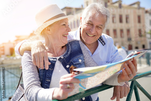 Senior couple of tourists looking at city map