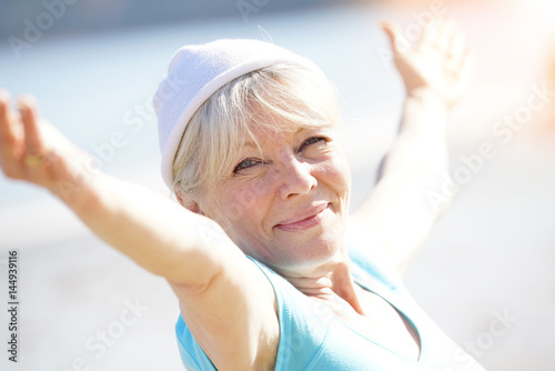 Senior blond woman doing yoga exercices on the beach photo