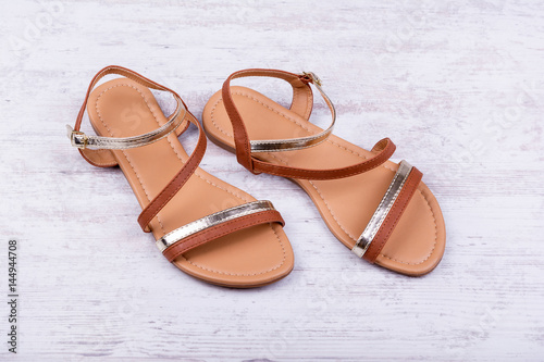 Pair of women's sandals on a white wooden background
