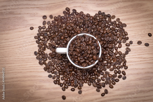 TOP VIEW: Coffee beans in a white cup and on the table.
