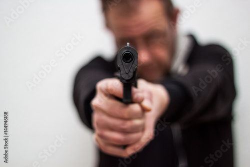 The man holding the gun in his hands and aim to another person, threatening to shoot © HappyLenses