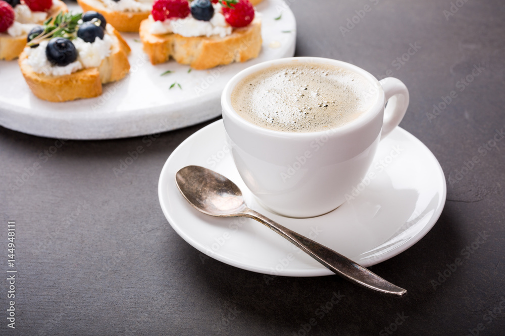 Cup of coffee with berry and goat cheese sandwiches on marble cutting board, top view, copy space. Cup of coffee with berry and goat cheese sandwiches on marble cutting board, top view, copy space.