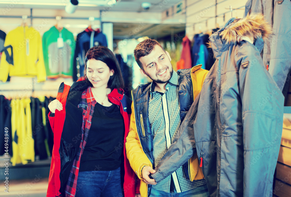 Young loving couple buying windcheater in store