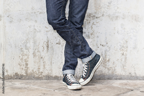 Regular Fit Straight Leg Jeans and Retro Canvas High Top Sneakers on Plaster wall background, selective focus (detailed close-up shot)